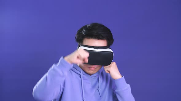 Young Asian Man Playing VR Game in Dark Blue Background. Chinese Young Hipster Wearing VR Headset.
