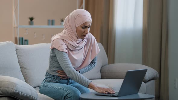 Young Islamic Arab Business Woman Muslim Girl in Hijab Sitting on Sofa Using Laptop at Home Working
