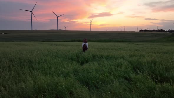 Young tourist walking in a field with windmills