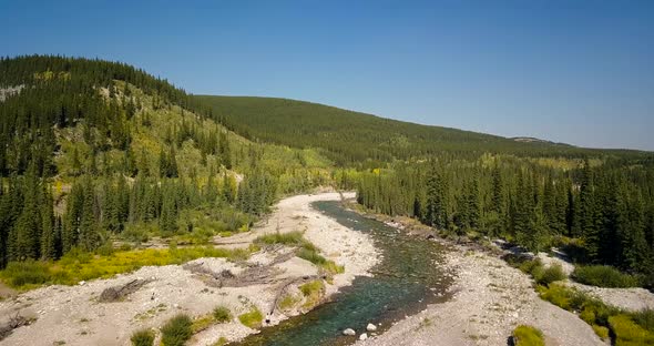 Aerial Daytime Medium Wide Shot Flying Forward Over The Bends Of A Swift Steep River Between Trees O