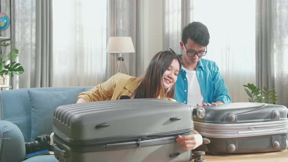 Happy Asian Couple Travelers Close Suitcase For A New Journey. Luggage For Travel Holidays