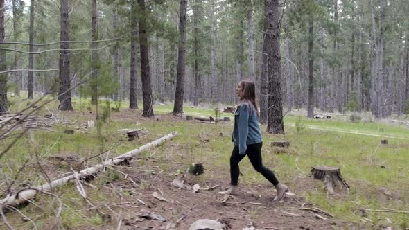 Young girl in denim jacket walking between trees in forrest