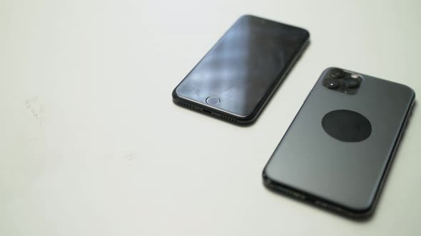 close up video of two dark smartphone on a white table