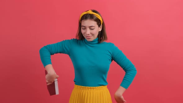 Gift Delivery. Smiling Girl Offering Wrapped Box To Camera Standing Over Red Background