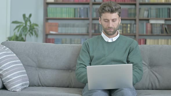 Excited Young Man Sitting on Sofa and Celebrating While Working on Laptop