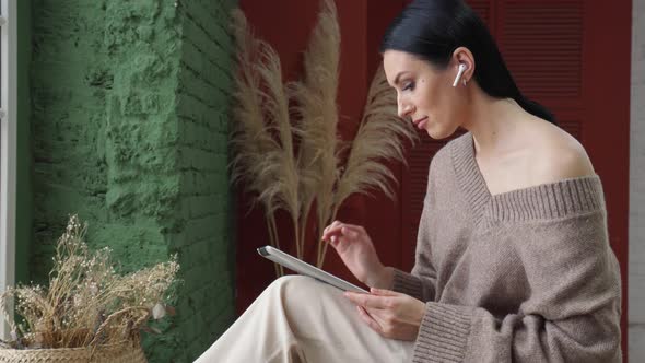 Beautiful Young Woman Using Computer Tablet Standing in Modern Living Room at Home