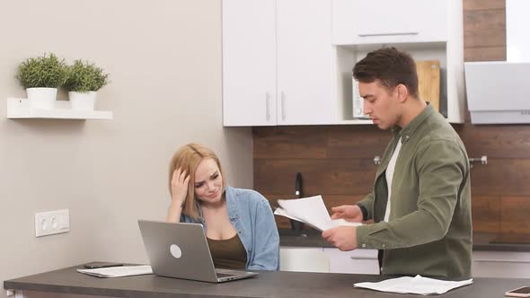 Disappointed Sad Couple Upset with Finance at Home Sitting with Laptop and Papers