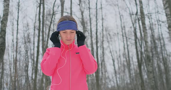 The Woman Before the Morning Winter Jog Inserts Headphones in the Ears and Is Preparing To Run