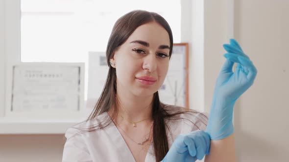 Portrait of a Young Caucasian Attractive Cosmetologist Puts on Gloves