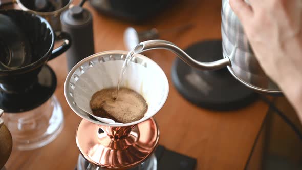 The barista is brewing coffee with traditional drip brewing equipment.
