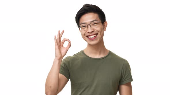 Portrait of Brunette Chinese Man Wearing Glasses and Basic Tshirt Showing Ok Symbol in Successful