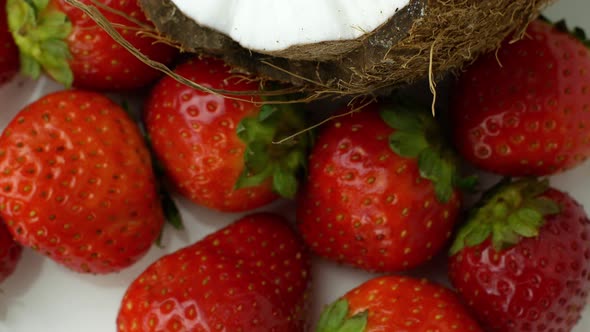 Tropical fruits coconut and strawberry rotates on a white background. Slow spinning exotic fruits