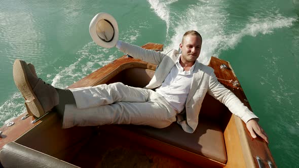 Lifestyle Portrait Of Young Successful Businessman Enjoying Freedom Riding Boat on Lake