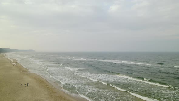 Captivating Ocean Waves With Tourist On Seaside Against Clear Sky In Wladyslawowo, Poland. - Wide Sh