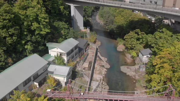 Aerial rising and tilt reveal shot revealing beautiful mountainous scenery, bridge and hotel in Joza