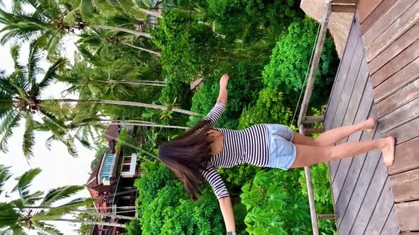 Young Girl Dance and Turns Around Her Head on Platform Near Palm Trees and Rice Terraces on Bali