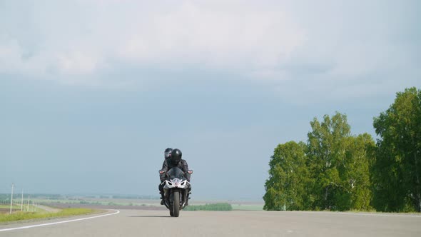 Cyclist with Passenger Rides Motorcycle at Countryside