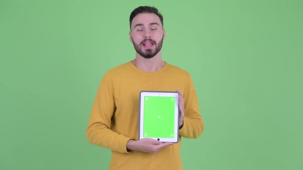 Happy Young Handsome Bearded Man Talking While Showing Digital Tablet