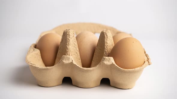 Eggs disappear from small Cardboard egg box on white background. Stop motion animation