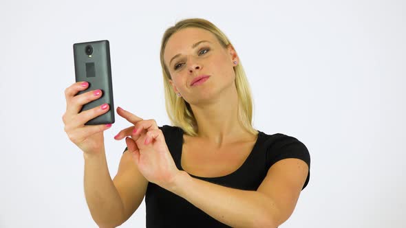 A Young Beautiful Woman Takes Selfies with a Smartphone - White Screen Studio