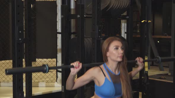 Young Athletic Woman Doing Squats with a Barbell Working Out at the Gym