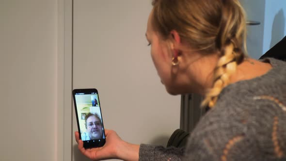 Young Girl Using Smartphone to Talk to Her Mother Via Video Conference