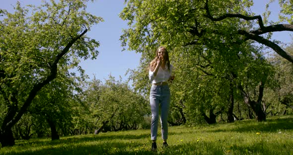 Young Beautiful Girl Walking in the Field on a Summer Day. Around It Green the Grasses and Green