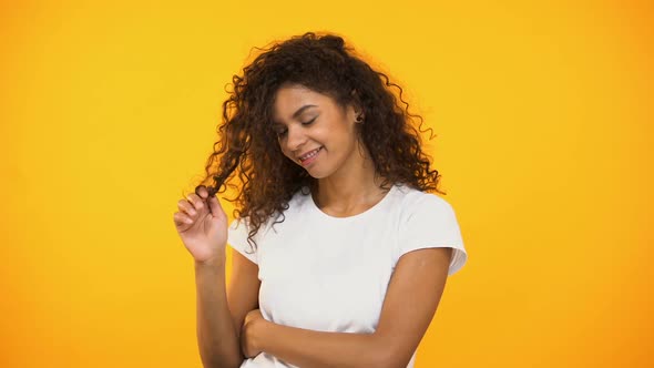 Coquettish Smiling Mixed-Race Woman Twisting Curls on Finger, Flirting at Camera