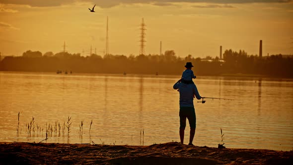 A Father and His Son on Fishing Together - the Boy Sitting on His Father Shoulders - Sunset
