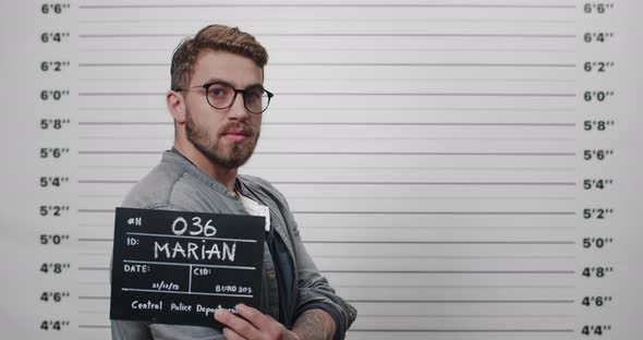 Side Profile Mugshot of Man with Beard and Mustache Holding Sign 