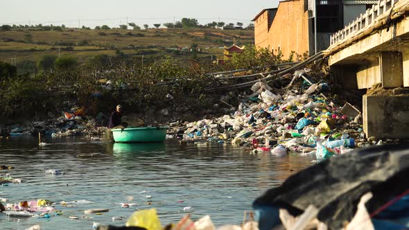 Local river in Vietnam filled with plastic waste. Person dropping fishing net into water