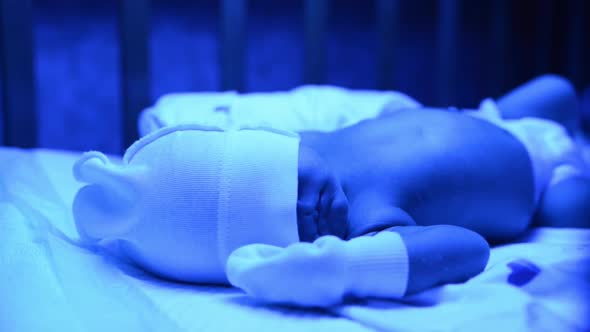 Newborn Having a Treatment for Jaundice Under Ultraviolet Lamp in Home Bed