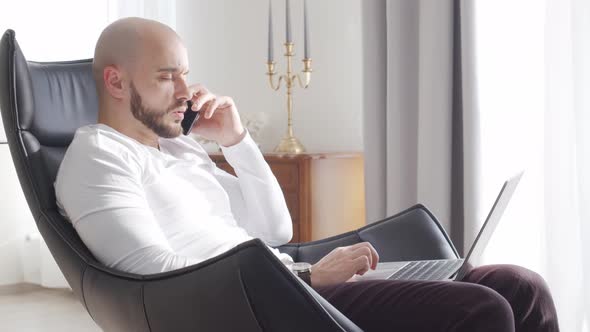 Bearded businessman working at home sitting in armchair. Business and investments concepts.