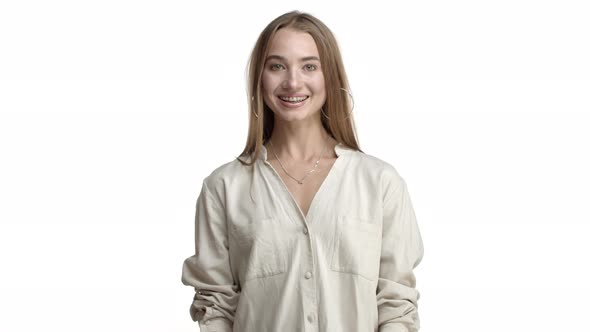 Happy Adult Woman with Long Fair Hair Wearing Beige Blouse and Necklace Saying Yes and Nodding in