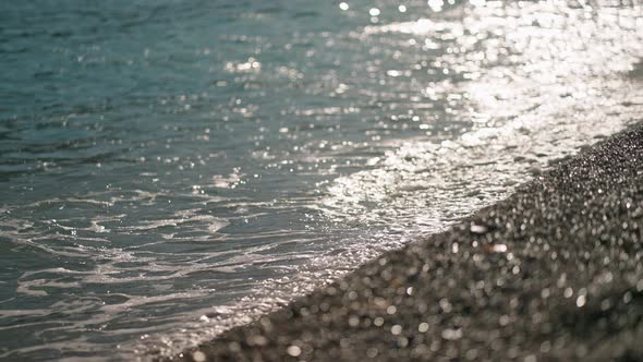 Close Up Slow Motion Ocean Sea Waves Rolls on Shore of Pebble Beach at Afternoon