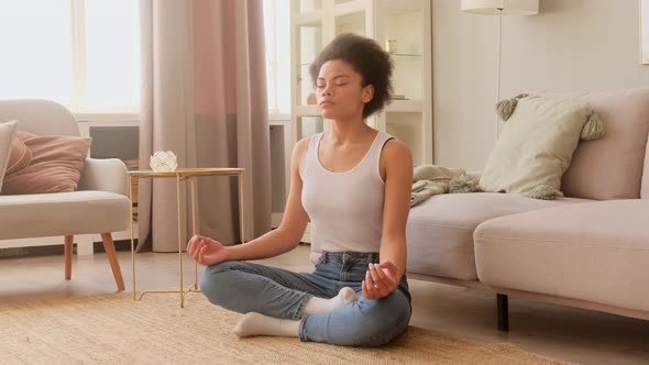 Black african american woman  meditating while sitting at home. Calm female taking deep breath