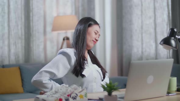 Asian Female Footwear Designer Having A Backache While Working On A Laptop At Home