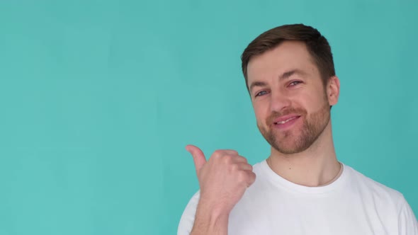 Handsome Male Guy Pointing His Thumb at Empty Space for Copy Isolated Background in Studio