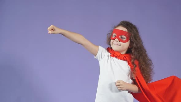 Cheerful Little Girl Wearing Red Mask and Cloak Isolated Purple Background