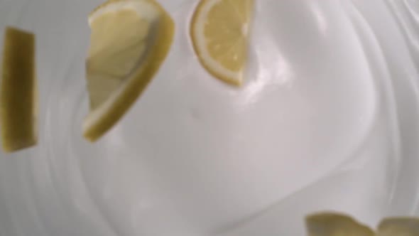 Sliced fresh lemons rain on yogurt in slow motion - High-angle shot