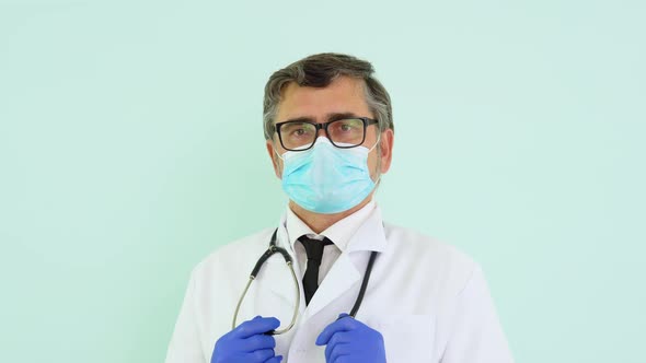 Portrait of a Senior Doctor in White Suit and Protective Mask on Blue Background