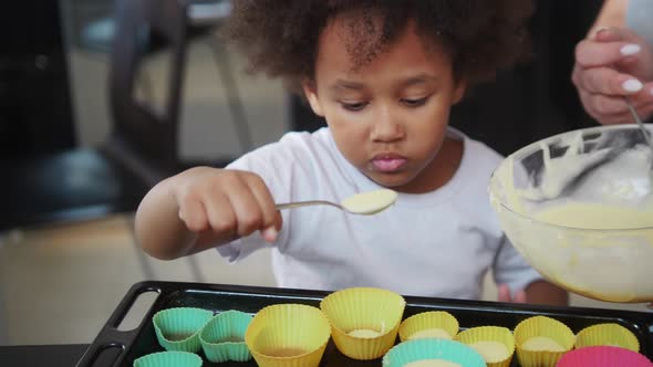 Little Black Girl with Her Mother Lays Down the Dough in the Small Cake Moulds