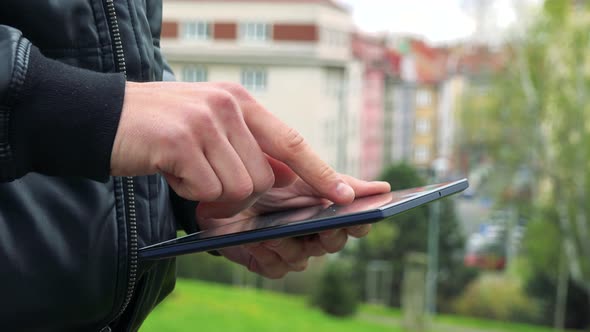 Man Stands and Works on Tablet Computer - Detail of Hands with Tablet Computer