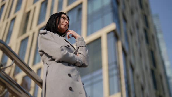 Successful Middleaged Woman in Grey Coat is Standing in Modern District in Autumn Day in City