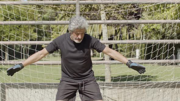 Focused Elderly Sportsman Standing in Football Goal Outside