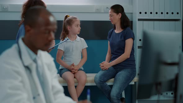 Woman Nurse Having Conversation with Little Kid and Mother