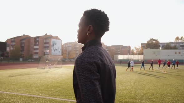 A Cheerful Young African American Woman Goes on the Treadmill of the City Stadium and Smiles