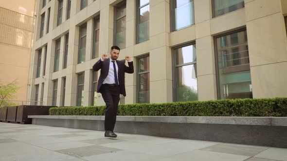 Happy Businessman Is Dancing on the Street Near the Office Center Wearing Suit Celebrating His