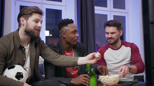 Multiethnic Guys Which Eating Popcorn During Watching Sport Game on TV