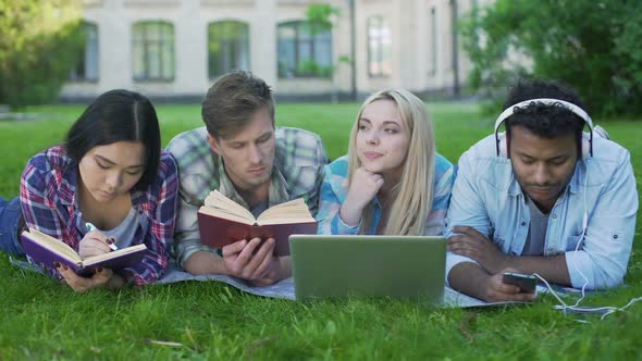 Multi-Ethnic Men and Women Doing Homework on Grass on Campus, Higher Education